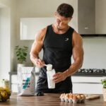 Sportif préparant un shaker de protéines dans sa cuisine après l'entraînement