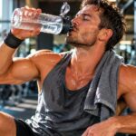 Sportif qui s'hydrate après une séance de musculation en salle