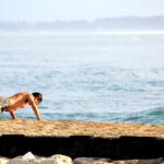 Homme athletique realisant des pompes sur une plage au bord de l ocean